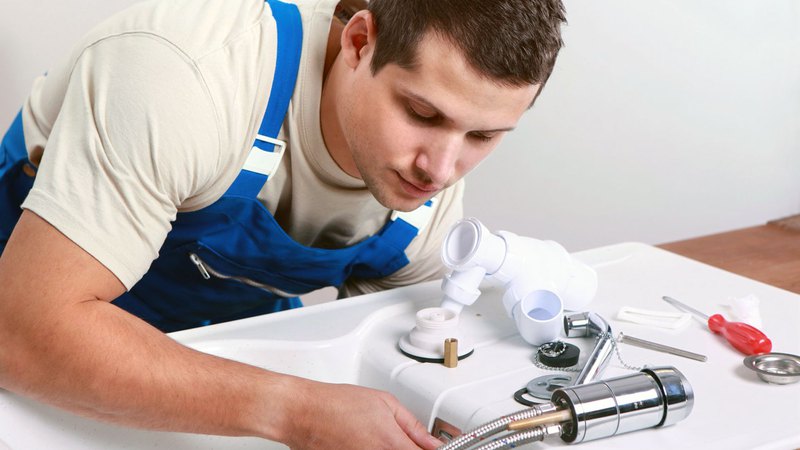 skilled plumbing service specialist assembling a kitchen sink faucet 