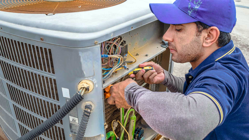 Here is the job performed by AC repair contractors: a technician at work fixing the outside unit.