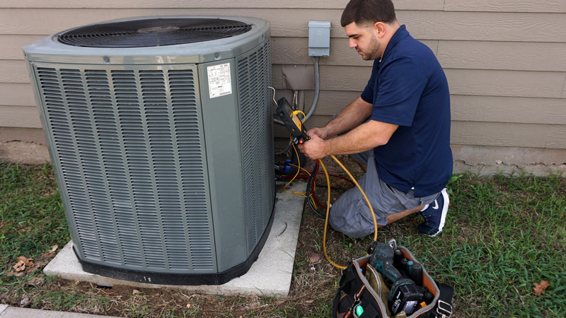 AC repair services in progress: a technician is working with the outside unit using proper tools