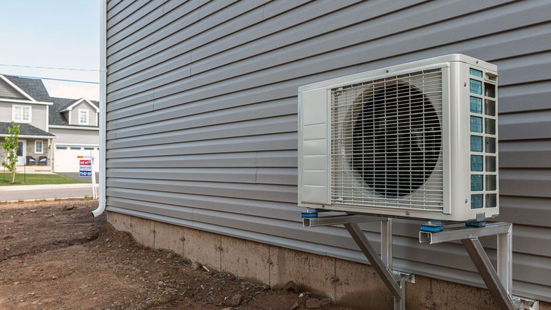 An outside unit of the mini-split heat pump system, mounted on a wall with triangular brackets